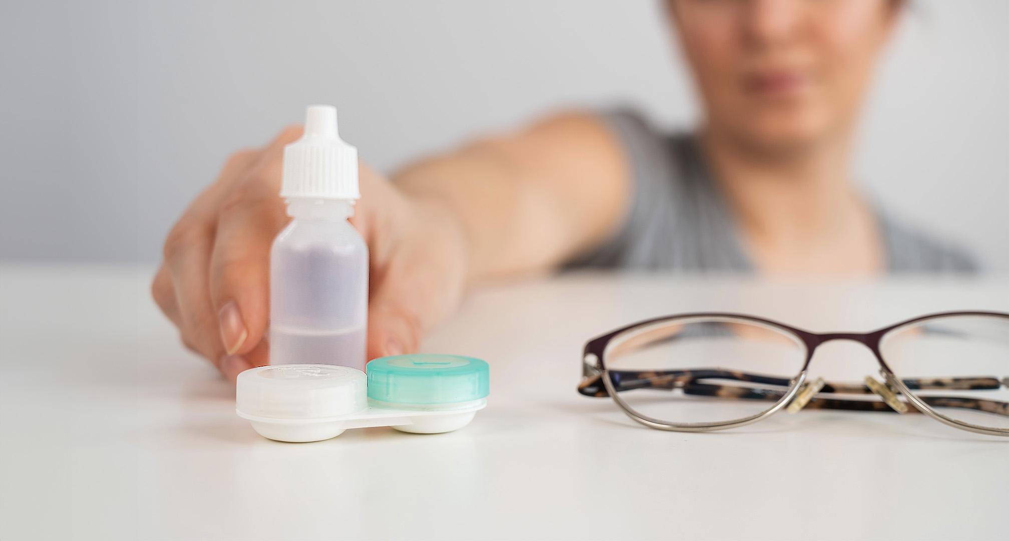 detailný obrázok očných kvapiek, puzdra na kontaktné šošovky a okuliarov na bielom stole