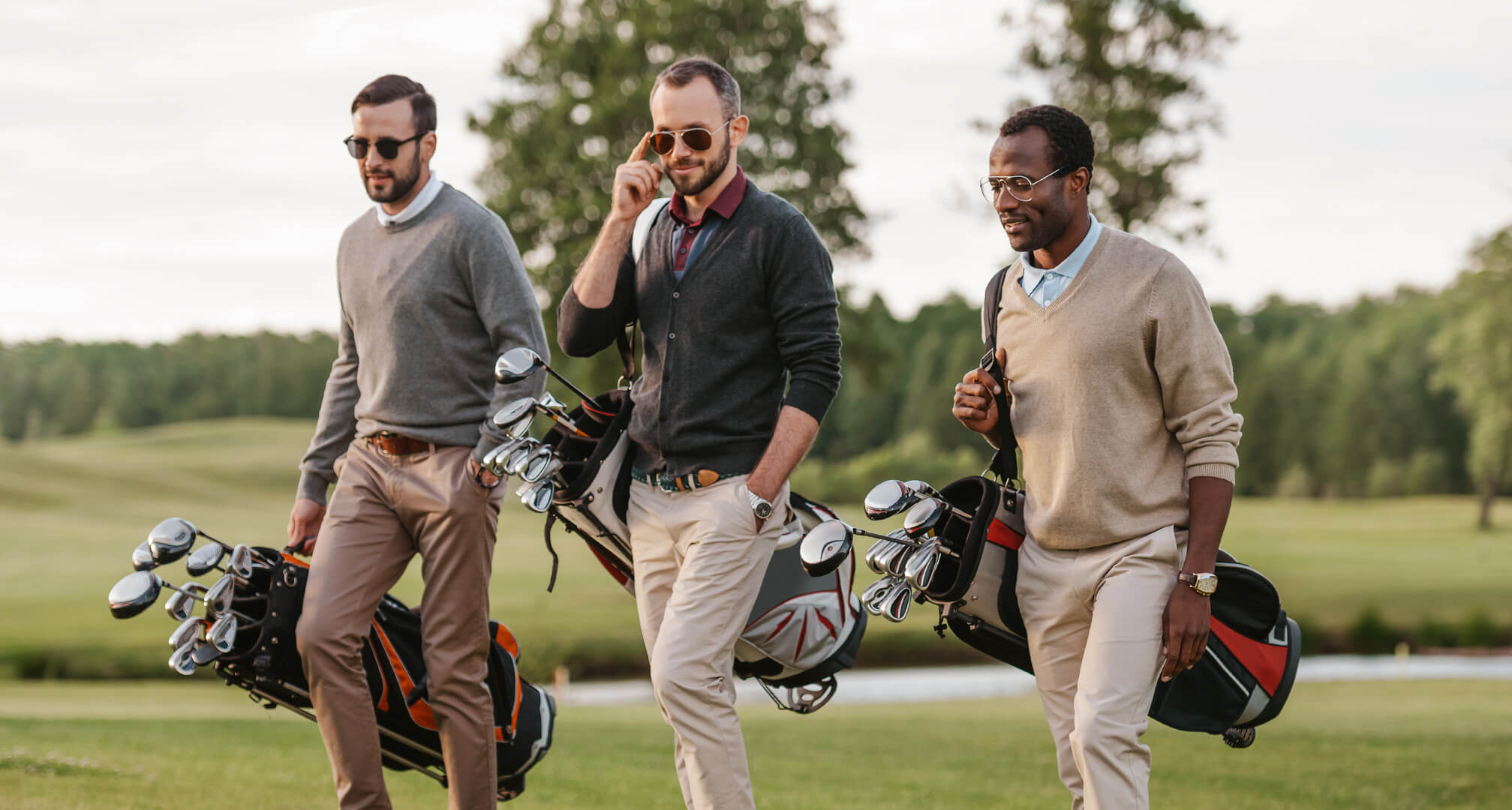 tři lidé hrající golf se slunečními brýlemi a golfovými vaky
